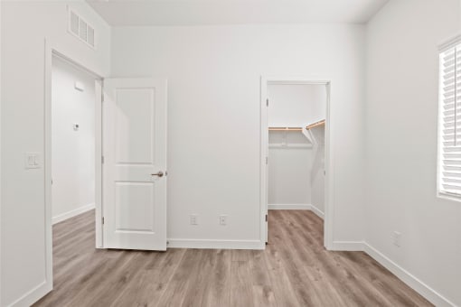 an empty bedroom with white walls and wood flooring