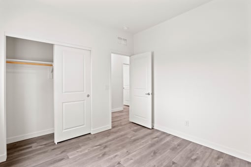 a bedroom with white walls and doors and a wood floor