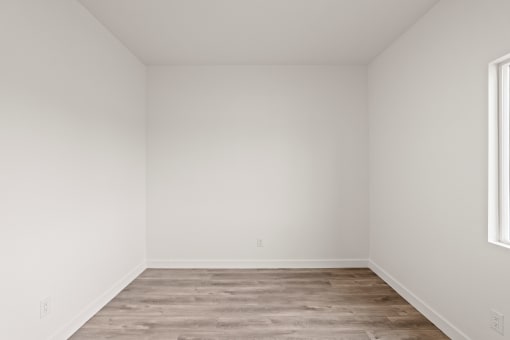 an empty room with wood floors and white walls