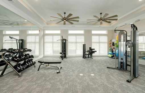A spacious home gym with a variety of equipment including treadmills, weights, and a bench press.