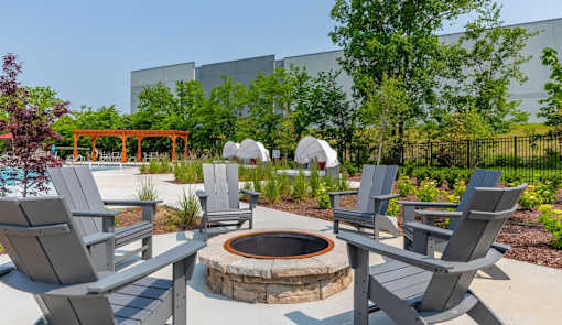 A fire pit surrounded by chairs in a backyard.