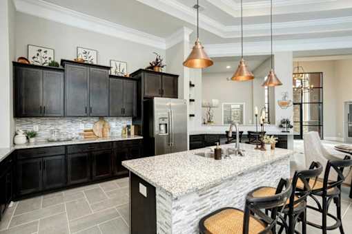A kitchen with a marble countertop and black cabinets.