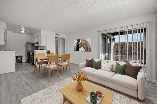 A living room with a white couch, a wooden coffee table, and a dining table with chairs.