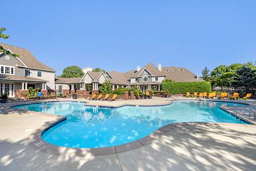 A large swimming pool surrounded by lounge chairs and a building in the background.