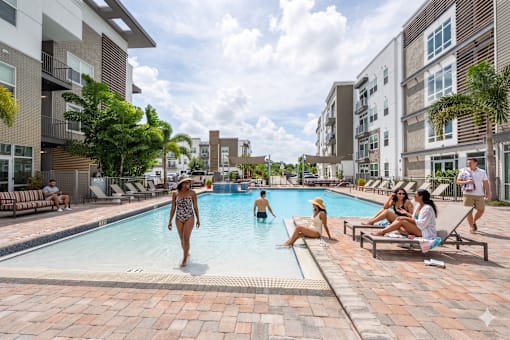 People are enjoying the outdoor pool area of a residential building.