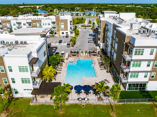 A swimming pool surrounded by apartment buildings and palm trees.