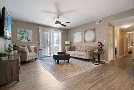 A living room with a white couch and a television on the wall.