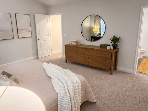 A bedroom with a round mirror and a wooden dresser.