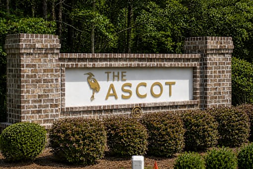 A sign that says The Ascot in gold letters on a white background.