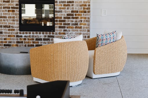 Two tan couches with pillows in front of a brick wall.