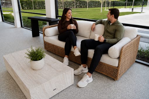 Two people sitting on a couch with a plant on a coffee table.