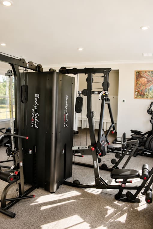 A gym with a variety of equipment including a squat rack and a leg press machine.