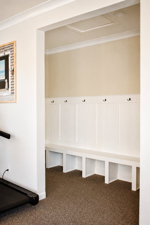 A white bench with a black handle is in a room with a brown carpet.