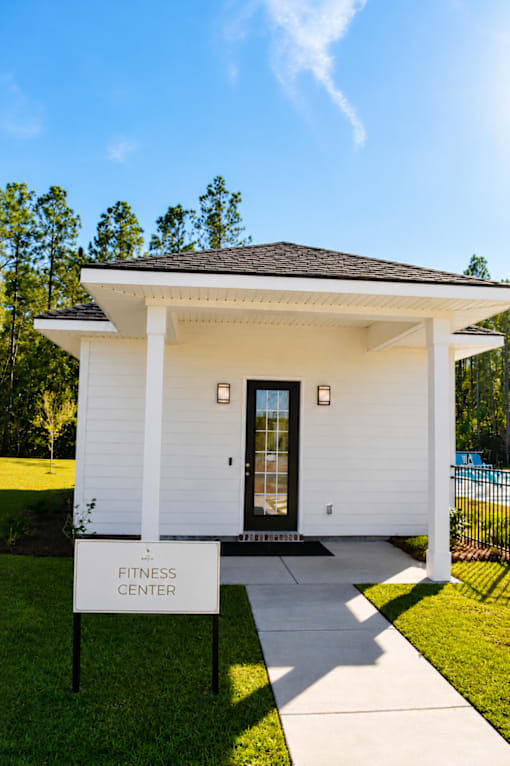 A small white building with a black roof and a sign that says Fitness Center.
