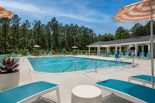 A pool with blue water and white lounge chairs.