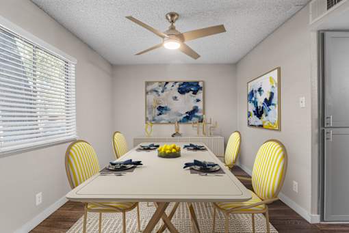 A dining room with a white table and yellow chairs.