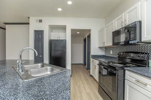 a kitchen with granite counter tops and black appliances