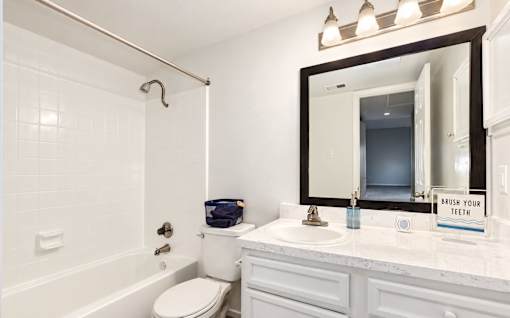 A bathroom with a toilet, sink, and mirror.
