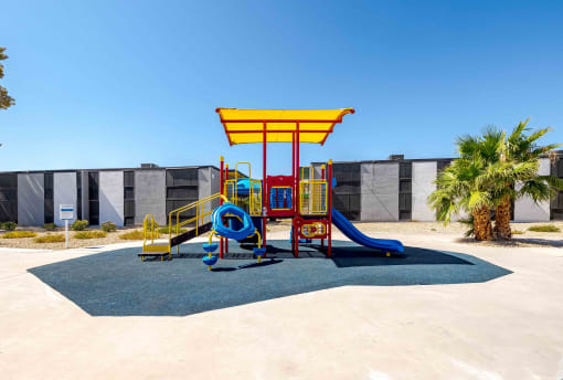 a colorful playground in front of a building with palm trees