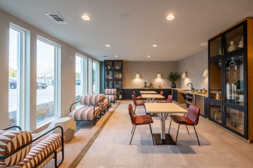 a lounge area with tables and chairs and large windows