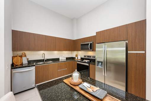 A modern kitchen with a stainless steel refrigerator and wooden cabinets.