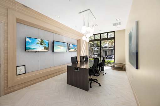 A modern office space with a reception desk, chairs, and a view of the outdoors.