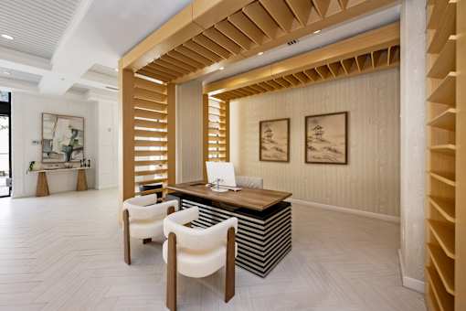 A room with a desk and chairs with a striped wall behind it.