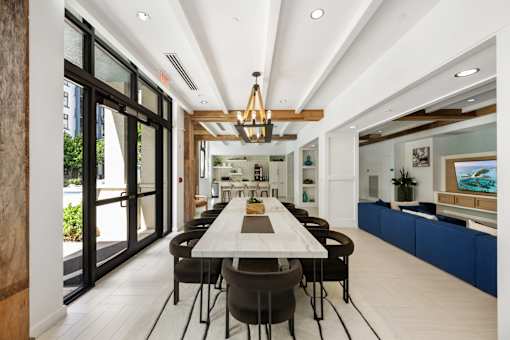 A long table with chairs is in the middle of a room with a large window.