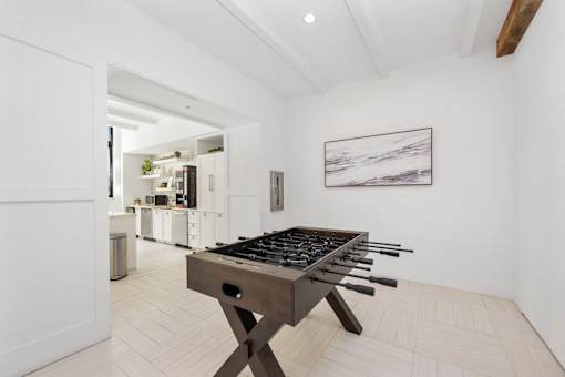 A modern kitchen with a wooden table and a painting on the wall.