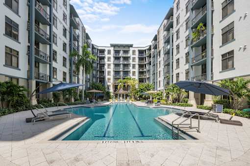 A swimming pool surrounded by apartment buildings on a sunny day.