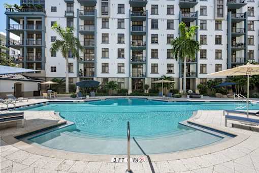 A swimming pool in front of a white apartment building.