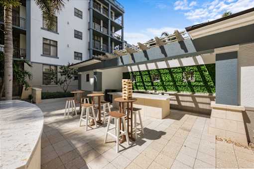 A patio with a table and chairs is surrounded by a building and trees.