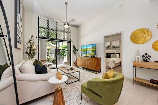 A living room with a white couch, a green armchair, and a TV on a wooden cabinet.