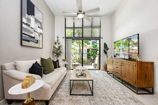 A living room with a white couch, a coffee table, and a flat screen TV.