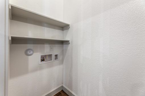 A white wall with a shelf and a light switch.