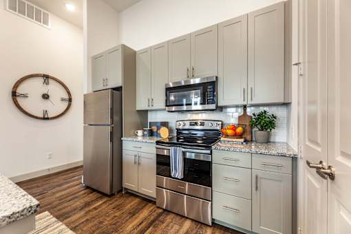 A kitchen with a stainless steel refrigerator, oven, and microwave.