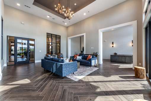 A large, modern living room with a blue couch and a wooden floor.