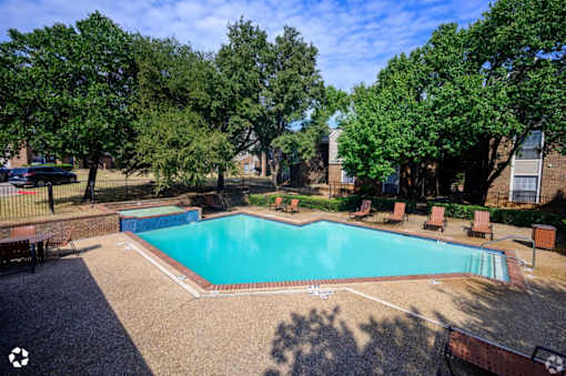 A swimming pool surrounded by trees and a fence.