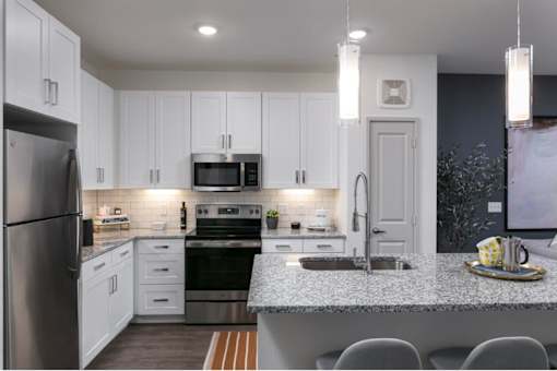 A modern kitchen with a granite countertop and stainless steel appliances.