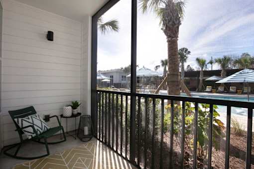 A balcony with a chair and a table with a plant on it.