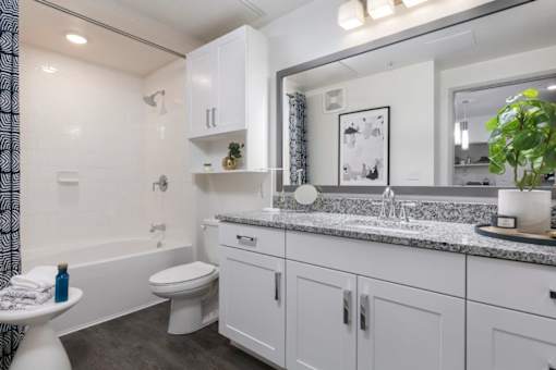 A white bathroom with a toilet, sink, and mirror.