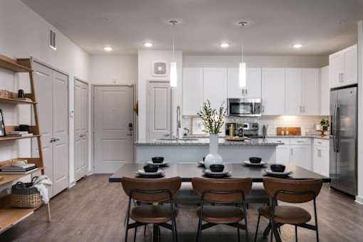 A modern kitchen with a dining table set for two.