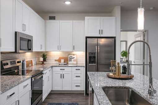 A modern kitchen with white cabinets and stainless steel appliances.