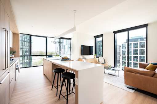 A modern kitchen with a bar stool and a white island.