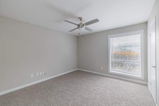 A room with a ceiling fan and a window with blinds.