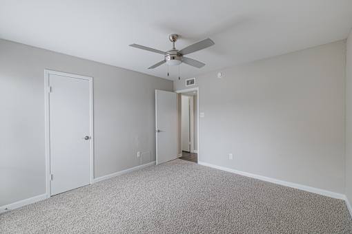 A room with a ceiling fan and carpeted floor.