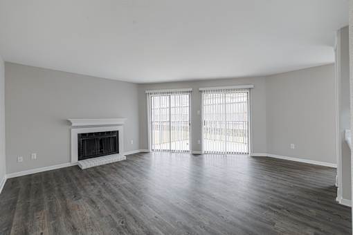A large empty room with a fireplace and sliding glass doors.