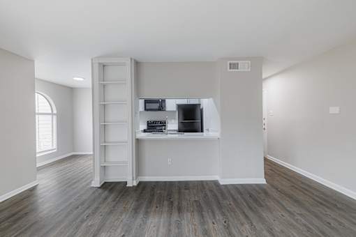 A room with a wooden floor and a white cabinet with a microwave on top.