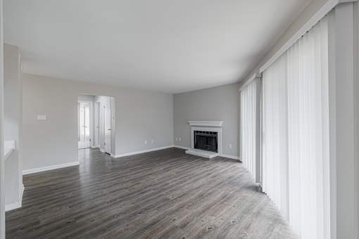A spacious room with a fireplace and wooden flooring.