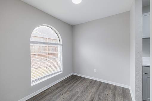 A room with a large arched window and wooden flooring.